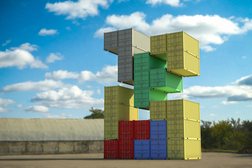Cargo containers shaped like tetris game pieces float in the air against a backdrop of blue skies and puffy clouds.
